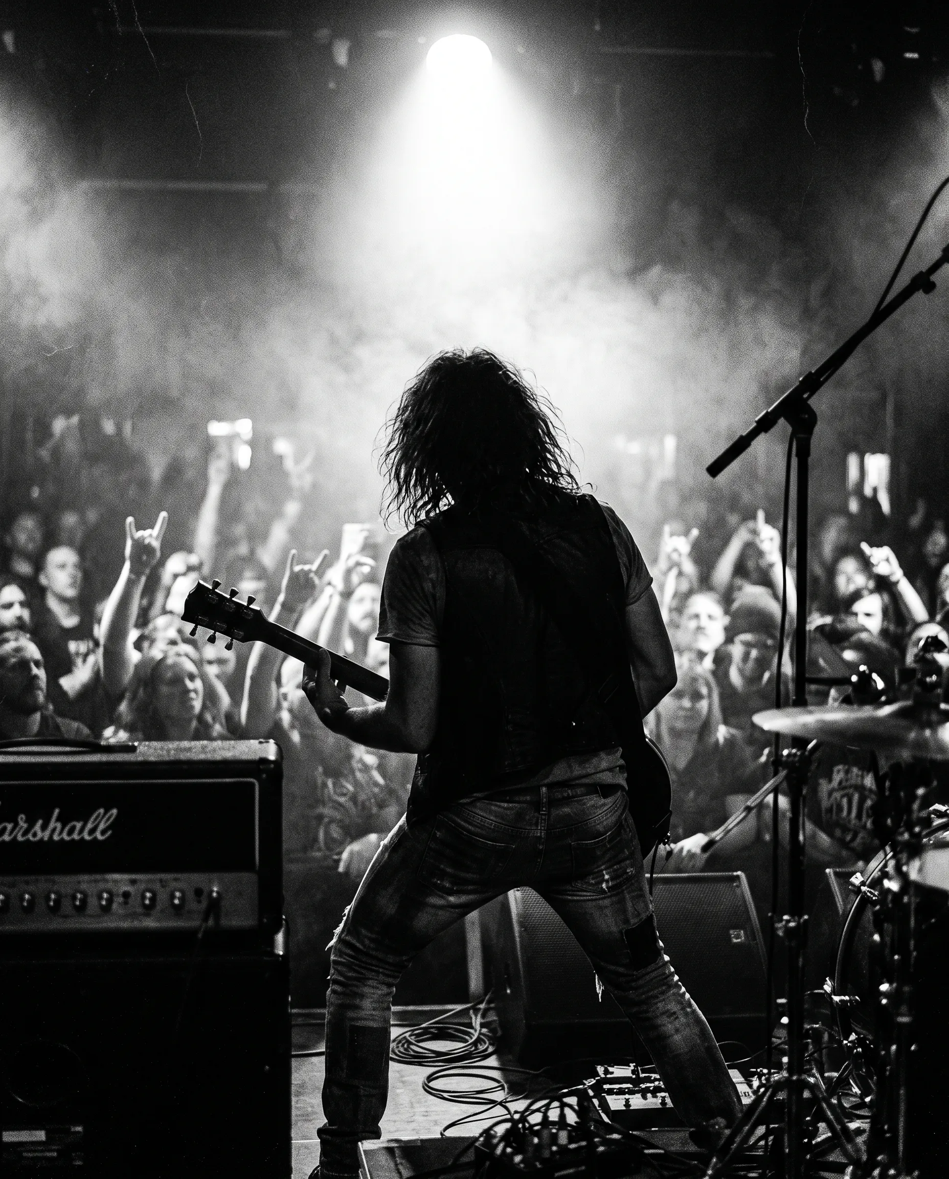 Guitarist på scenen foran publikum i modlys